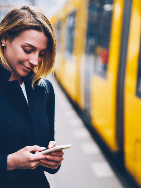 Woman using phone by a train